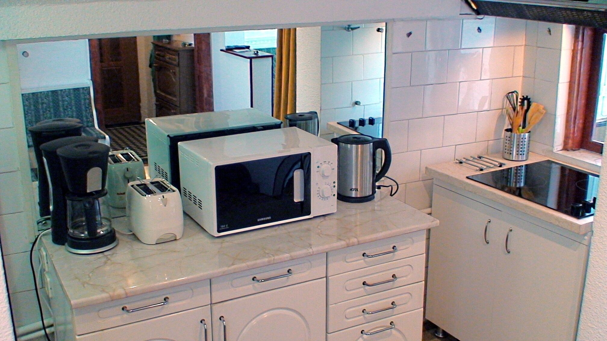 Une cuisine compacte équipée d’un four à micro-ondes, d’un grille-pain, d’une machine à café et d’une bouilloire.