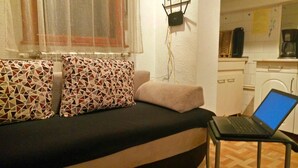A small living area with a sofa, a laptop on a table, and a kitchen in the background. - 4stars FRENCH EMBASSY One Bedroom Apartment, AMZEI historic downtown, very quiet (Bucharest)