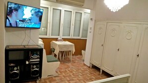 A room with a television mounted on the wall, a small table with a chair, and a wardrobe with decorative handles. - 4stars FRENCH EMBASSY One Bedroom Apartment, AMZEI historic downtown, very quiet (Bucharest)