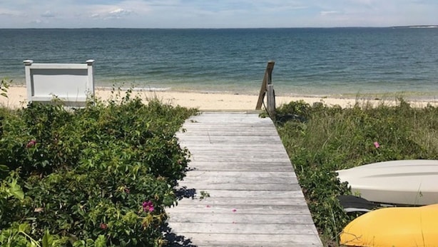 A wooden pathway leading to a beach with a white chair and a yellow kayak. - Southampton  PRIVATE Waterfront Estate!
 (Hampton Bays)