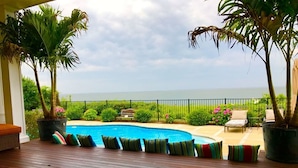 A poolside area with a wooden deck, lounge chairs, and potted plants. - Southampton  PRIVATE Waterfront Estate!
 (Hampton Bays)