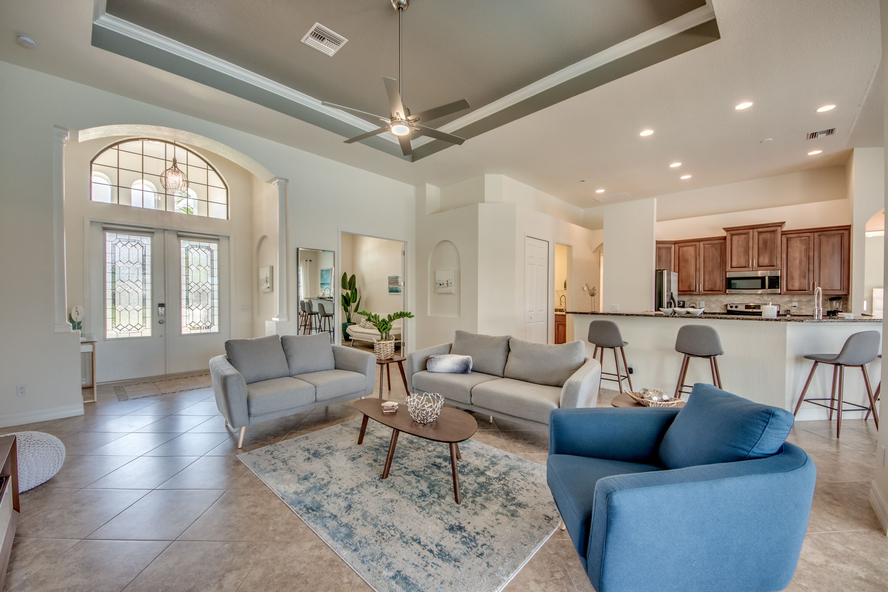 A spacious living room with a high ceiling, a dining area, and a kitchen.