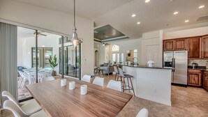 A modern kitchen with wooden cabinets, a stainless steel refrigerator, and a dining area with a wooden table and white chairs. - Villa Destiny, great villa with modern ambience, pool and spa facing south (Cape Coral)