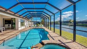 A covered swimming pool with clear views of a lake and a house in the background. - Villa Destiny, great villa with modern ambience, pool and spa facing south (Cape Coral)