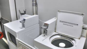 A compact, modern bathroom with a built-in washer and dryer, a small sink, and a toilet with a lid.