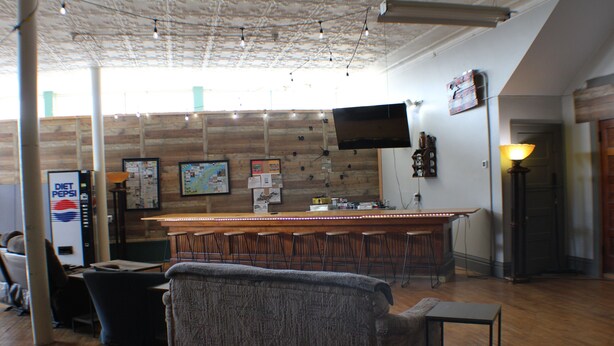 A bar area with stools, a counter, and a TV mounted on the wall. - 3BR on SXS Snowmobile Trail w/Full Bar, Walk to Dining &Bars, Near MTU &Houghton (South Range)