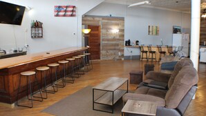 A bar area with stools, a sofa, and a television mounted on the wall. - 3BR on SXS Snowmobile Trail w/Full Bar, Walk to Dining &Bars, Near MTU &Houghton (South Range)