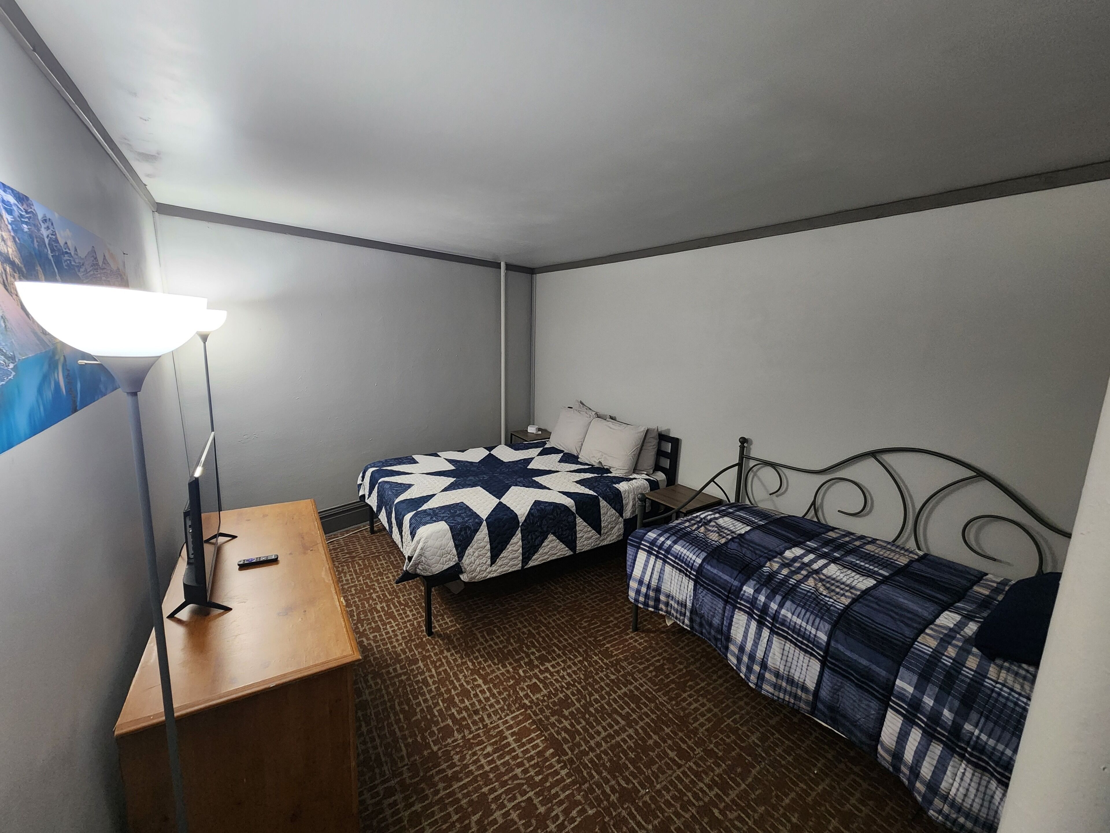 Une petite pièce, de taille modeste, comprenant deux lits simples, un bureau et une lampe.