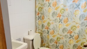 A bathroom with a toilet, a sink, and a shower curtain with a floral pattern. - Apartment in Rincon (Rincon)