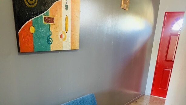 A blue sofa in a hallway with a tiled floor and a red door in the background. - Apartment in Rincon (Rincon)