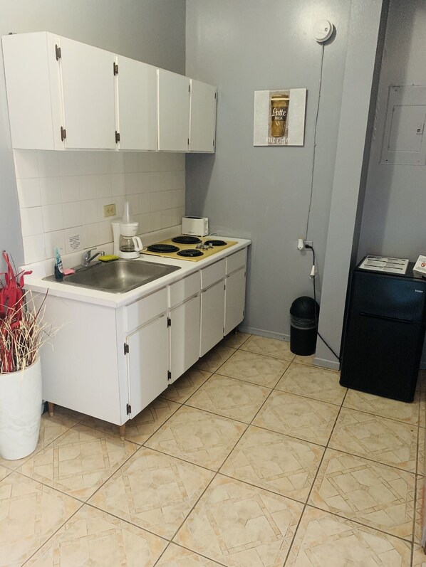 A compact kitchen with white cabinets, a stainless steel sink, a coffee maker, and a toaster. - Apartment in Rincon (Rincon)