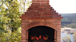 A brick-built outdoor oven with vegetables cooking inside, a sink, and a view of a river and forest in the background. - Hobbit House (bioclimatic and half-buried with green cover). (Alba de los Cardaños)