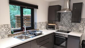 Eine moderne Küche mit integriertem Backofen, einer Mikrowelle und einer Edelstahl-Dunstabzugshaube.