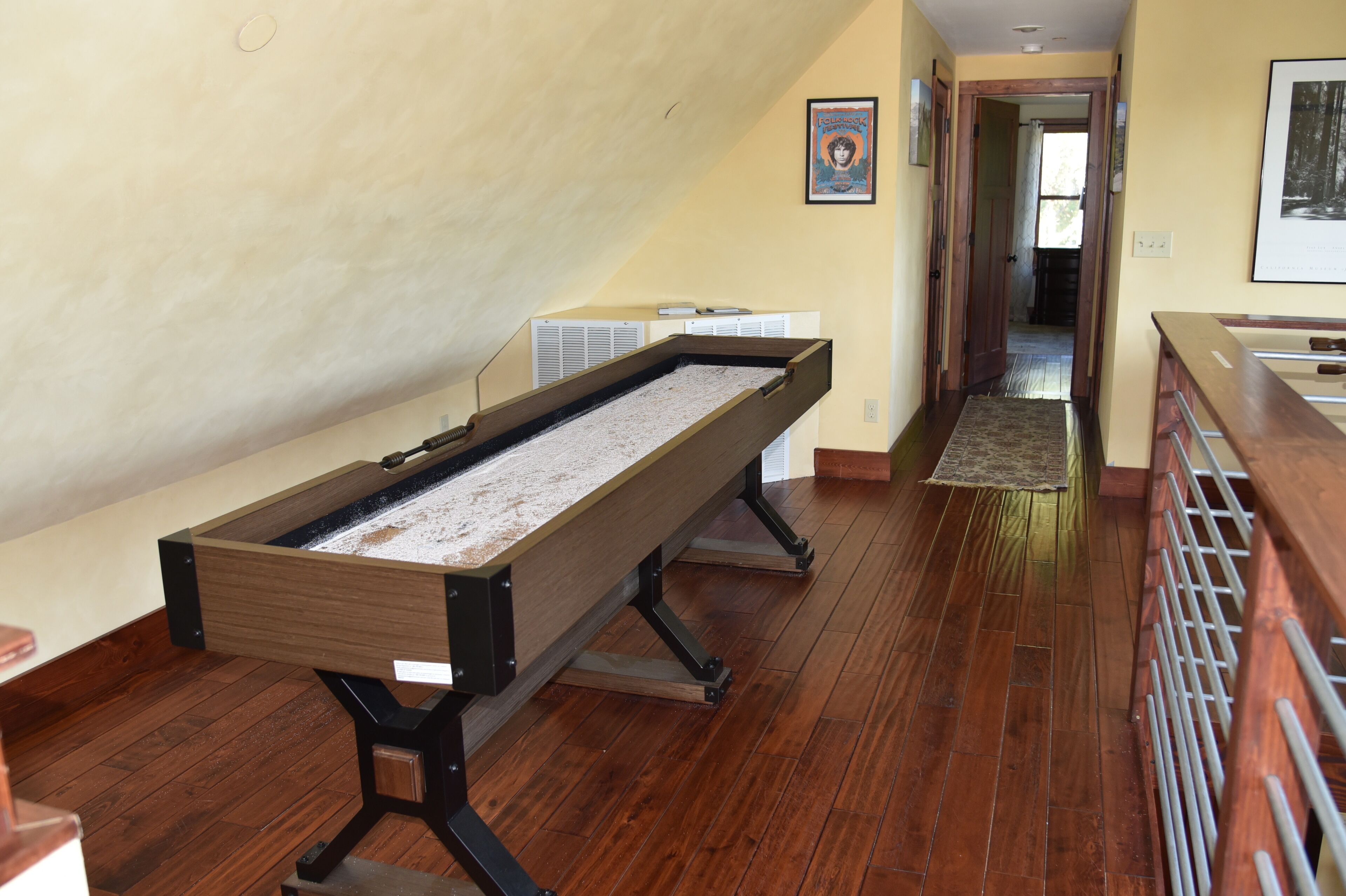 A pool table in a room with wooden flooring and a high ceiling.