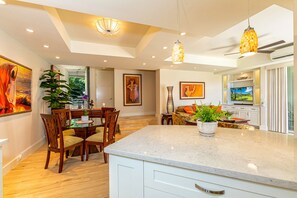 Cozinha moderna com bancada de mármore, cadeiras de madeira e iluminação pendente.