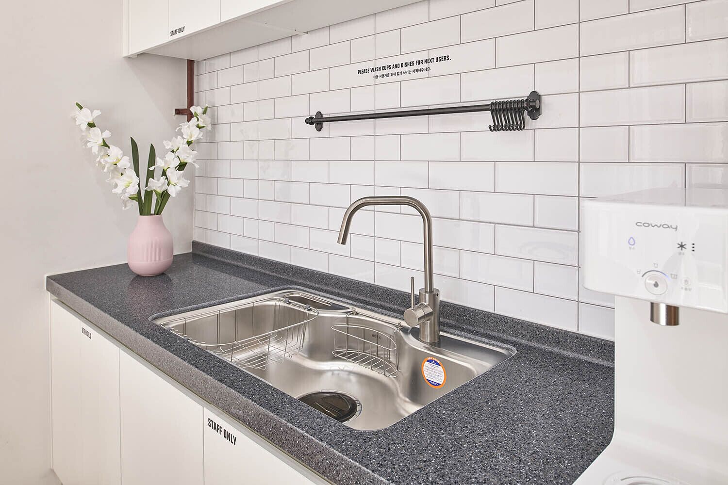 A kitchen with a double sink, a stainless steel faucet, a soap dispenser, and a towel rack.