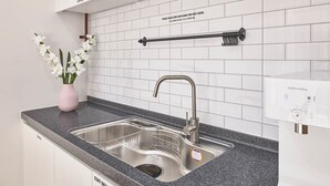 A kitchen with a double sink, a stainless steel faucet, a soap dispenser, and a towel rack. - Futon Guesthouse (Seoul)