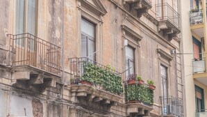A multi-story building with balconies, a red door, and parked cars in front. - Central Station House Riccardo (Catania)