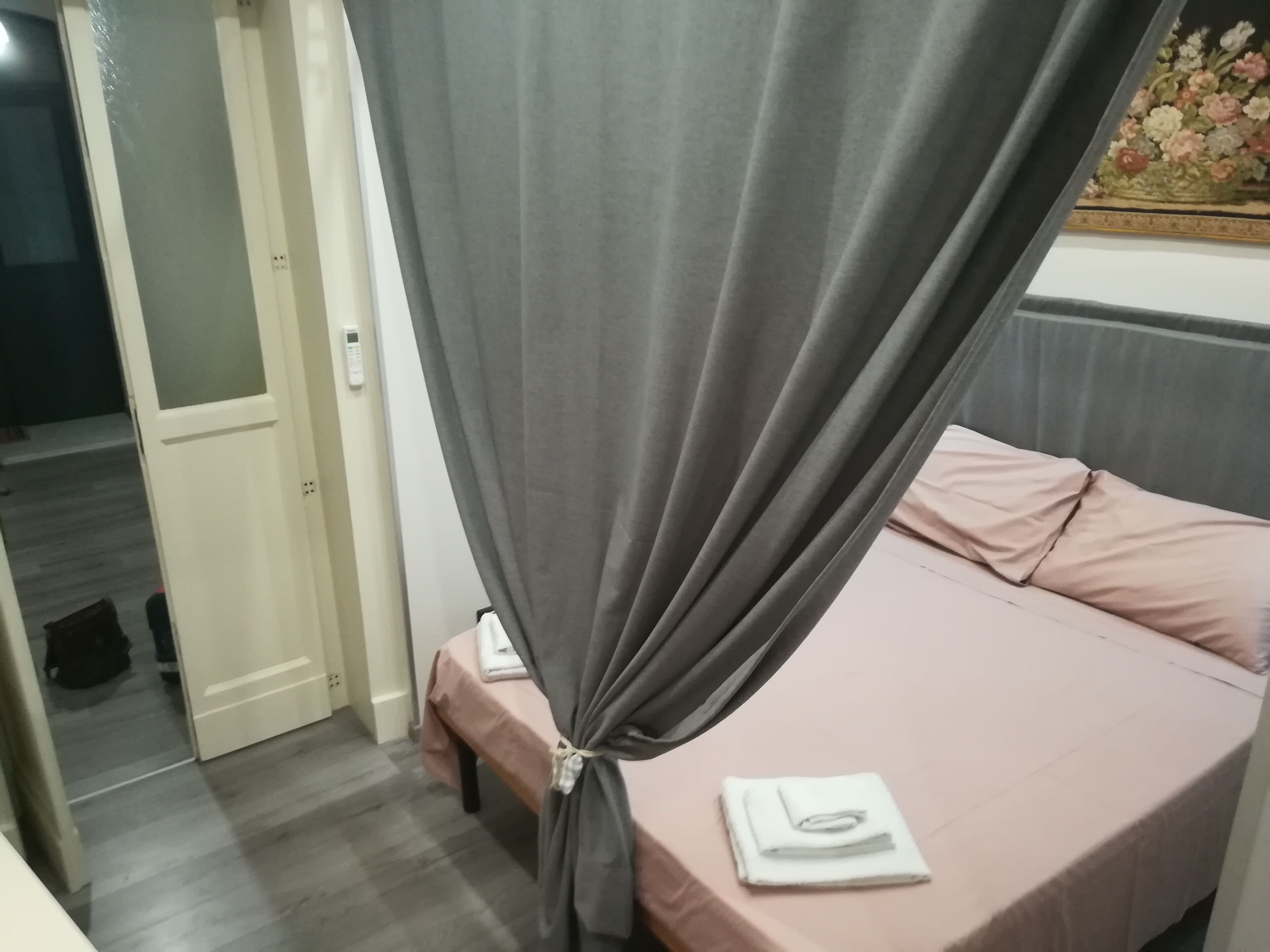 A bedroom with a bed, a bedside table, and a curtain.