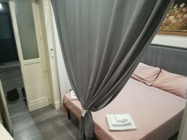 A bedroom with a bed, a bedside table, and a curtain. - Central Station House Riccardo (Catania)