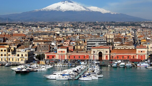 A coastal cityscape with a prominent snow-capped mountain in the background. - Central Station House Riccardo (Catania)