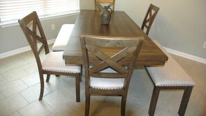 Una mesa de comedor con cuatro sillas de madera, un florero y un banco.