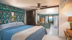 A bedroom with a large bed, a ceiling fan, and a view of the ocean through a sliding door. - Sapphire Beach Resort Rental (St Thomas)