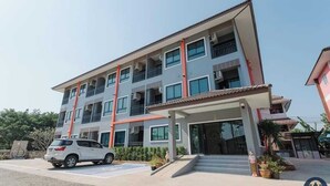 Un hôtel à plusieurs étages, doté d’un design moderne, comprenant des balcons, une entrée couverte et un espace de stationnement.