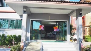 Une entrée moderne, avec un porche abrité, des portes vitrées et des ballons de couleurs vives.