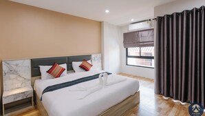 Une chambre d’hôtel avec un lit, une table de chevet et une fenêtre avec des rideaux.