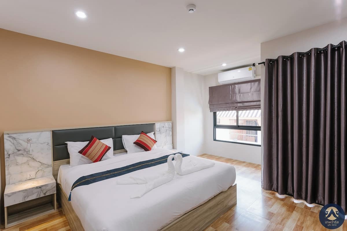 Une chambre d’hôtel avec un lit, une table de chevet et une fenêtre avec des rideaux.