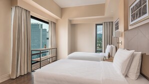A hotel room with two beds, a balcony with a view of the city, and a large window with curtains.