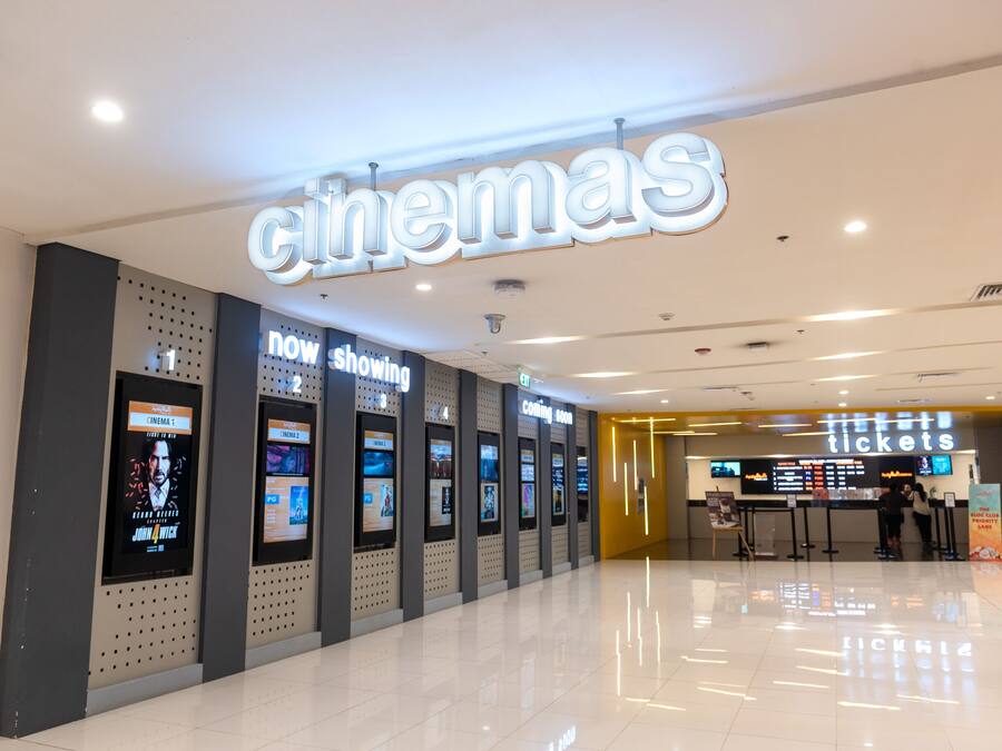 Cine de diseño moderno, con pantallas digitales y ventanilla de venta de entradas.