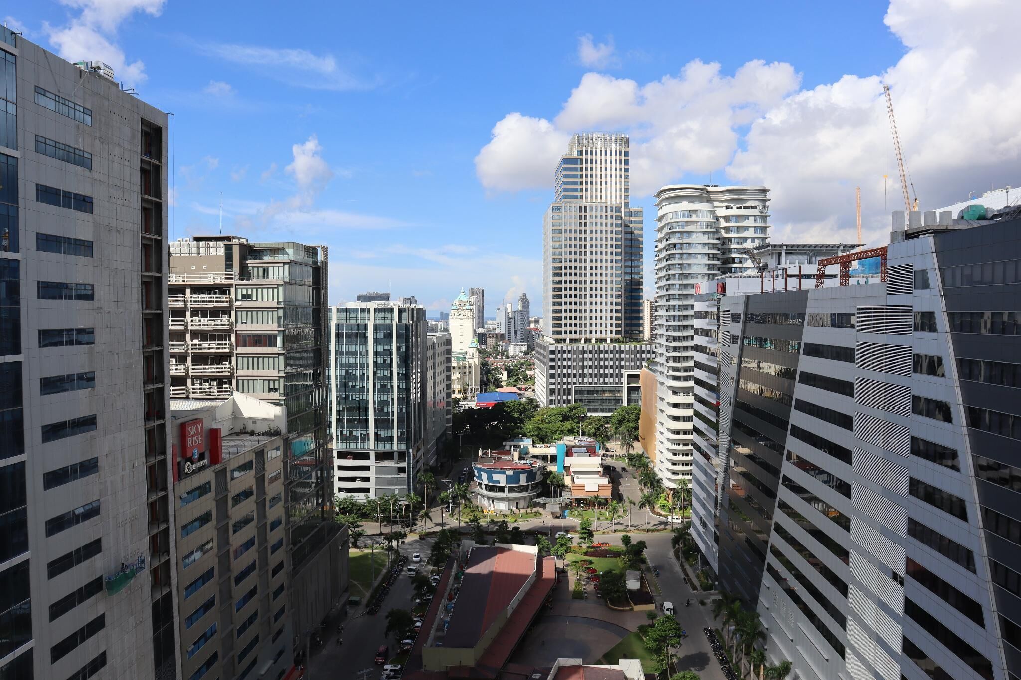 A high-rise urban area with modern buildings, a central roundabout, and a mix of commercial and residential structures.