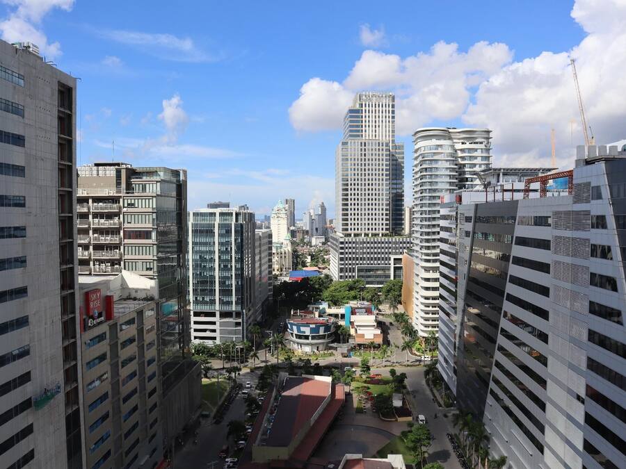 Un quartier urbain dense, caractérisé par de grands immeubles modernes, un rond-point central et un mélange de bâtiments commerciaux et résidentiels.