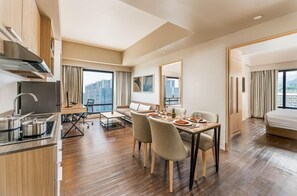 A modern hotel room with a dining area, kitchenette, and a large window with a city view. - Seda Central Bloc Cebu City (Cebu City)