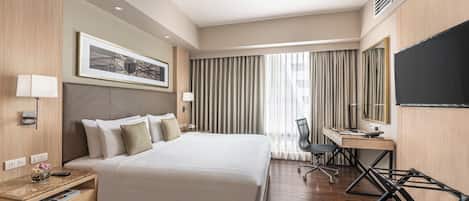 A modern hotel room with a large bed, a desk, a chair, and a television.