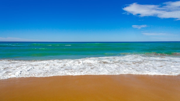 A beach with clear blue water and a sandy shore. - Beachouse  (Loch Sport)