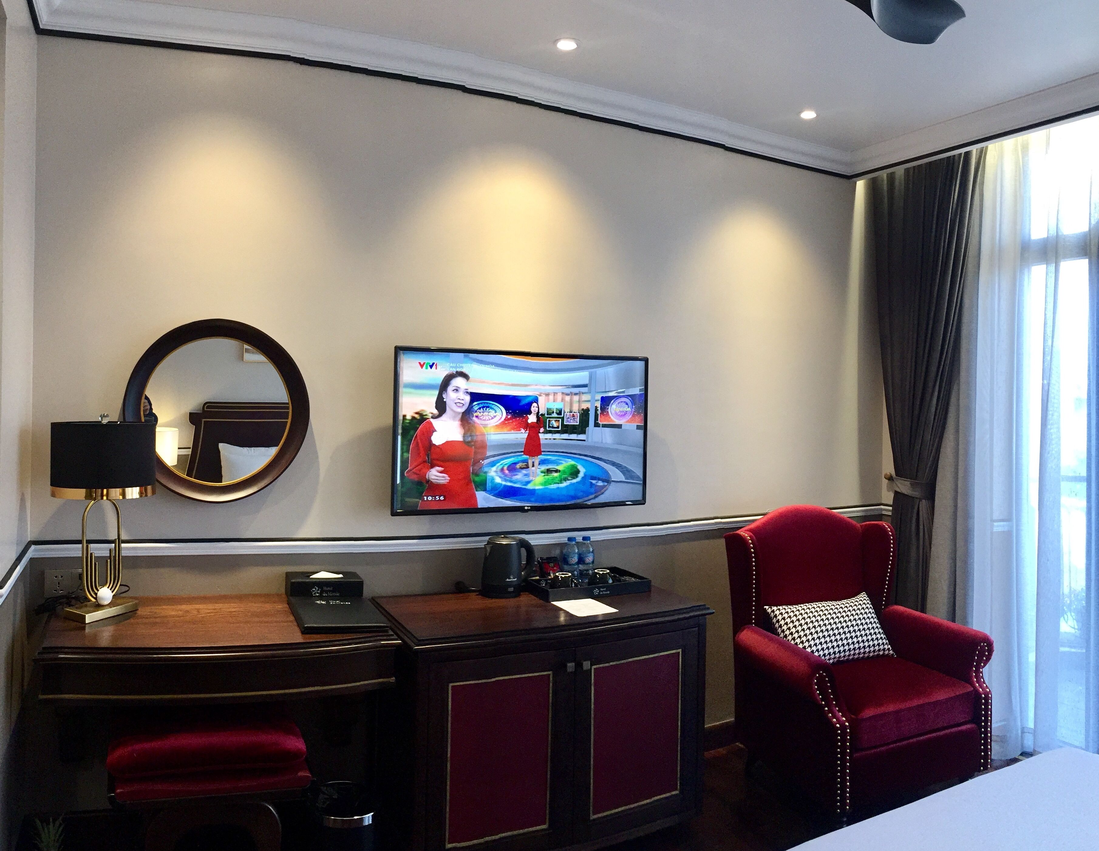 A hotel room with a TV, a desk, a chair, and a bed.