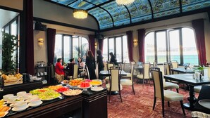 A restaurant with a high ceiling, patterned glass, and a buffet with various dishes.