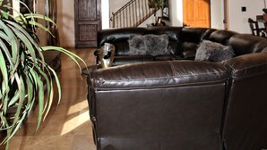 Un salon spacieux, doté d’un canapé en cuir, d’un ventilateur de plafond et d’un escalier menant à l’étage supérieur.