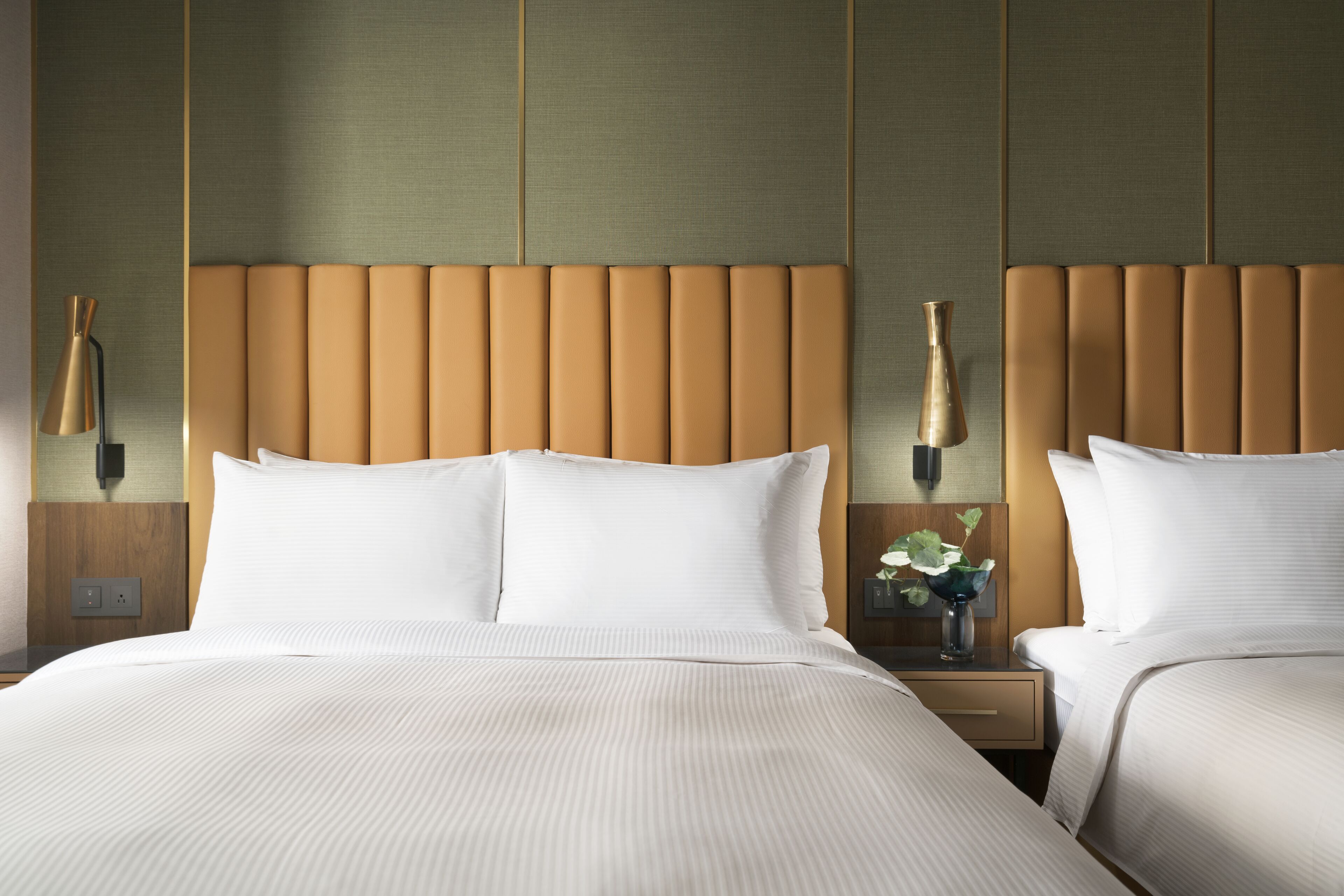 Una habitación de hotel con una cama grande, dos mesitas de noche y una lámpara de pared.