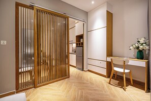 A modern kitchen with a refrigerator, wooden cabinets, and a dining area with a table and chairs. - The Art - Sunshine Apartment (Ho Chi Minh City)