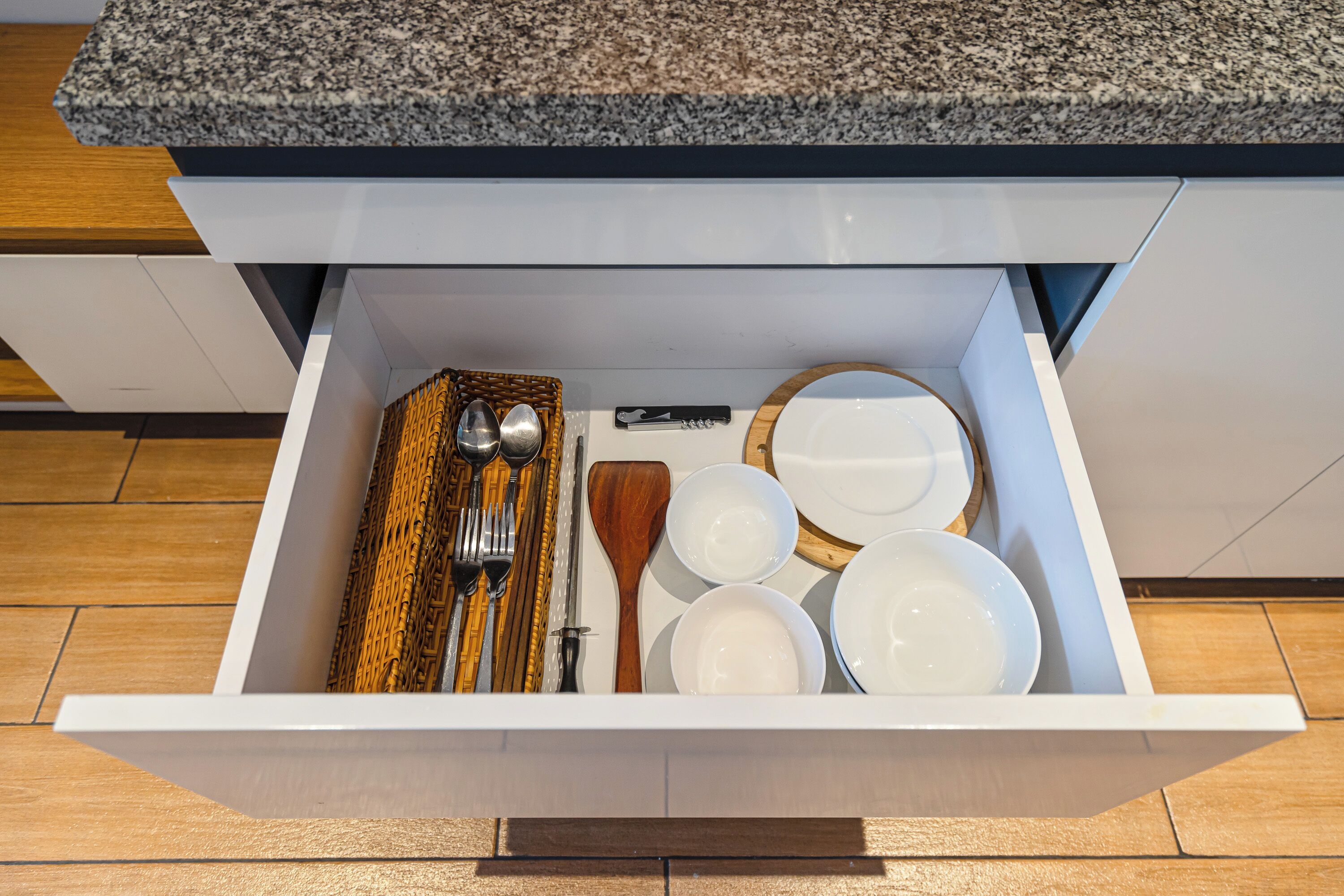 Un cajón de cocina con varios utensilios y vajilla.