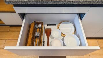 Un cajón de cocina con varios utensilios y vajilla.