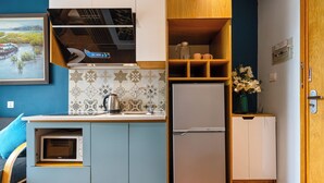 A compact kitchen with a built-in microwave, a stainless steel refrigerator, and a sink with a modern faucet. - The Art - Sunshine Apartment (Ho Chi Minh City)
