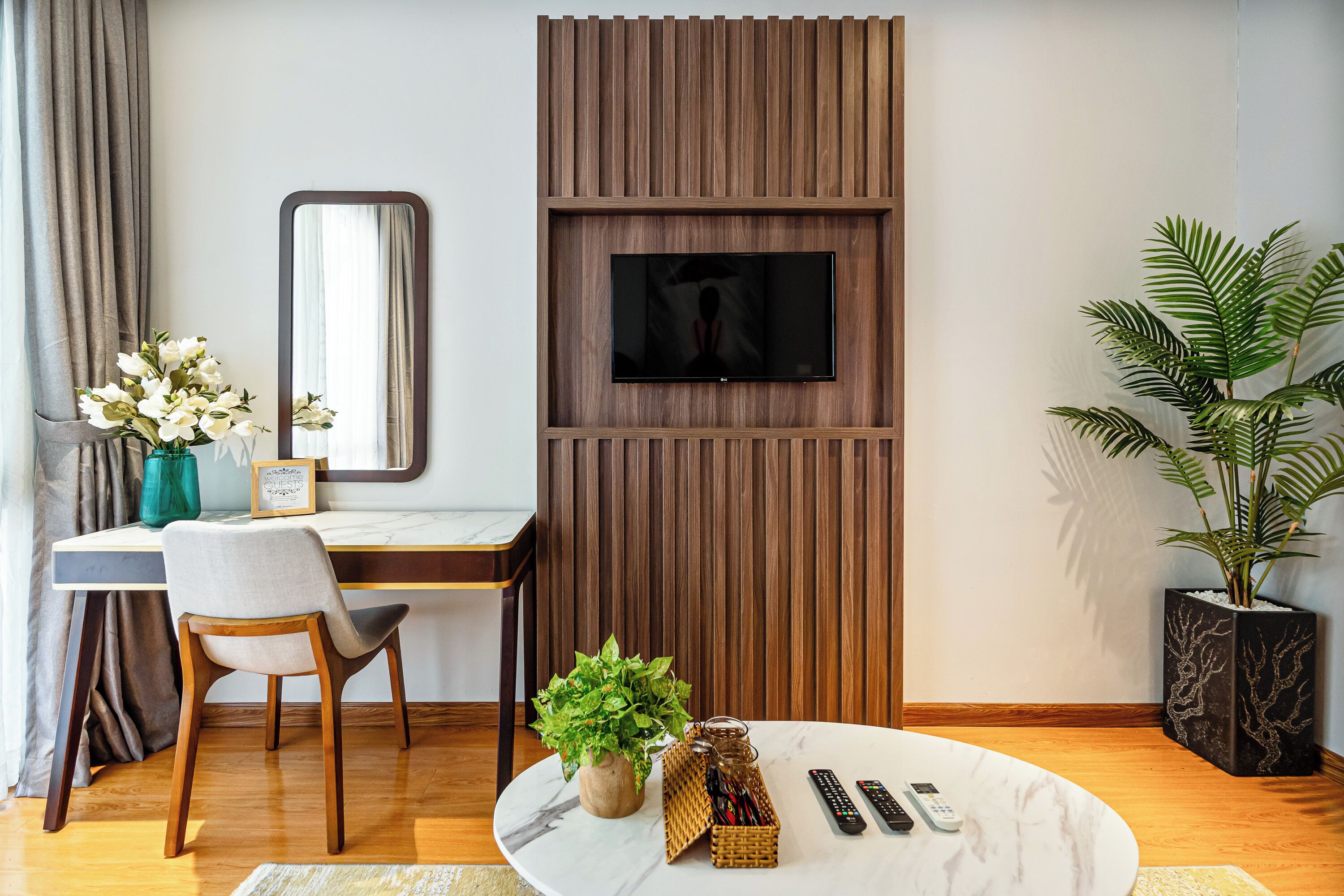 Una habitación moderna con escritorio, silla, televisor y plantas en macetas.