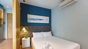 A hotel room with a bed, a nightstand, a wall-mounted lamp, and a painting. - The Art - Sunshine Apartment (Ho Chi Minh City)