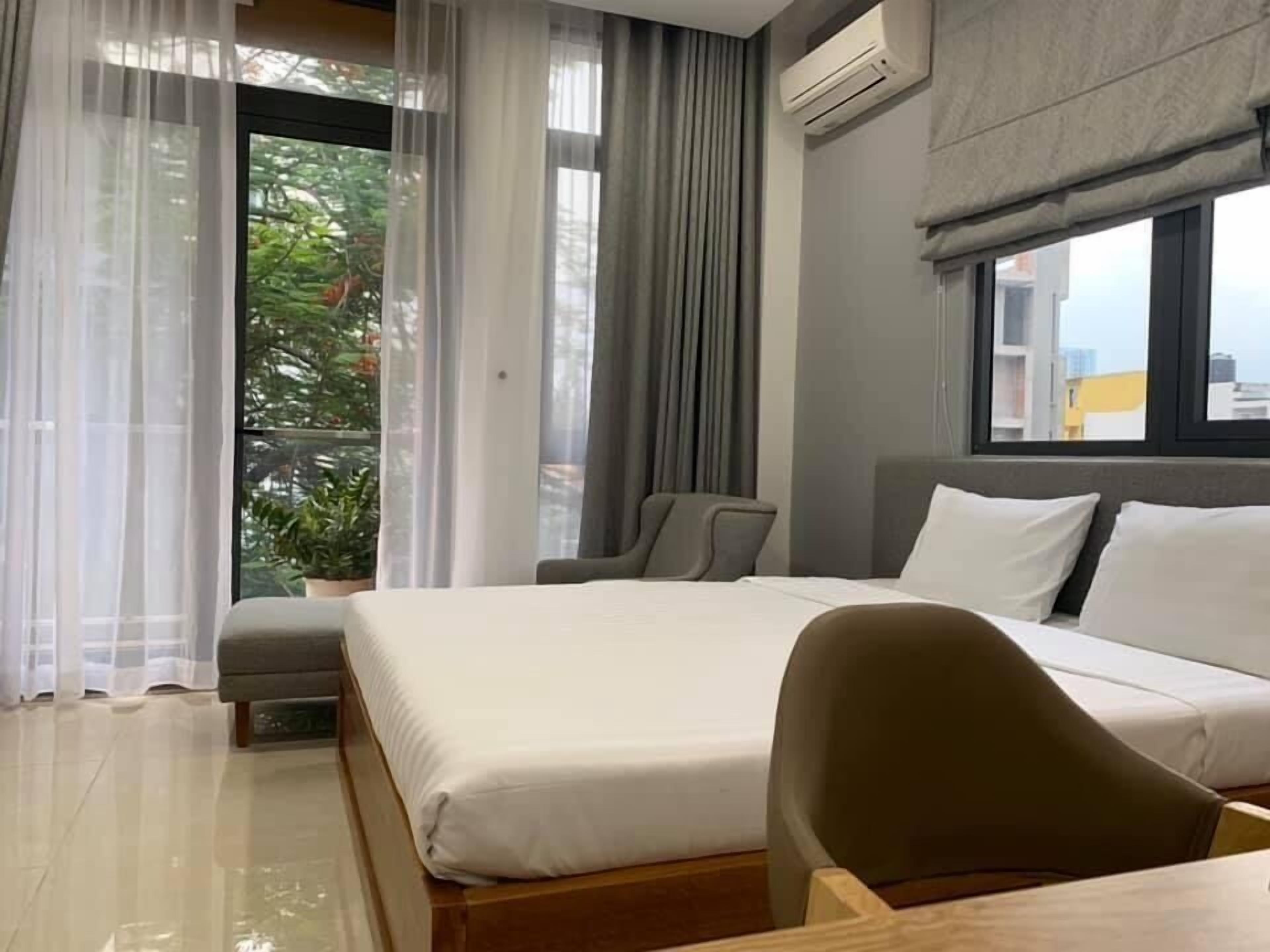 A hotel room with a bed, a desk, a chair, and a window with curtains.
