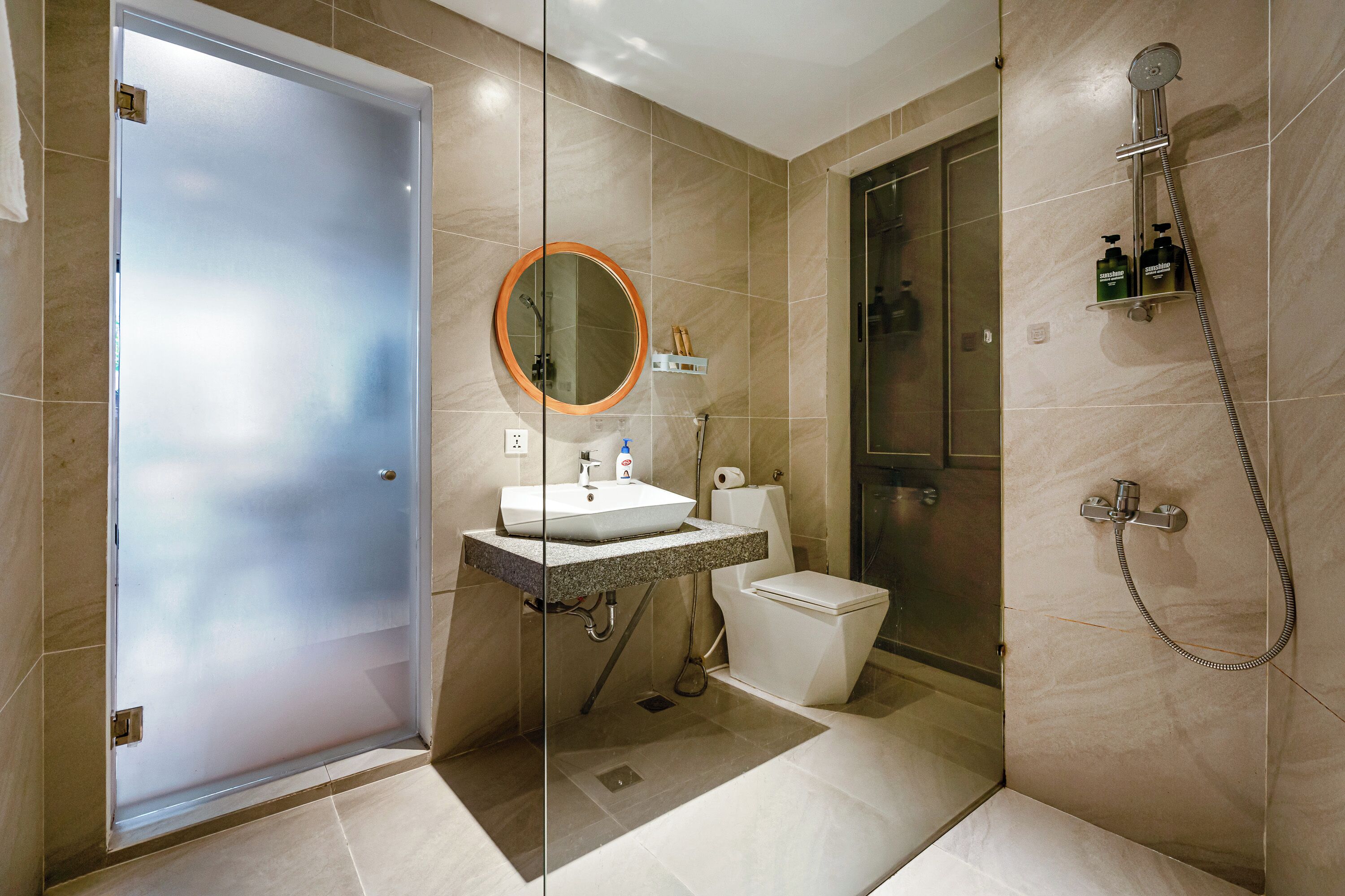 Een moderne badkamer met een glazen deur, een wastafel met spiegel, een toilet en een douche.